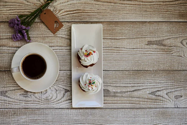 Dessert macaroons with cup of coffee on white wooden table.