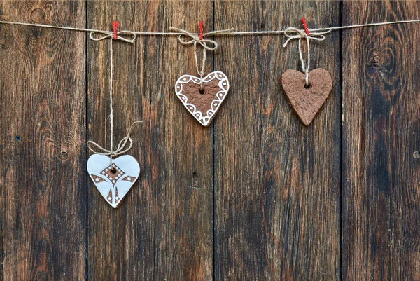 暗い木製の背景の前で縄に掛かっている心臓の形のジンジャーブレッド — ストック写真