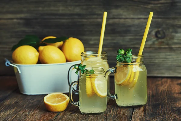 Nane ve buz ile ev yapımı limonata. Mason limonata rustik ahşap arka plan üzerinde kavanozları. Lezzetli ve sulu limonata, yararlı vitaminler ve antioksidanlar dolu. Sağlıklı ve detoks yaz içeceği.