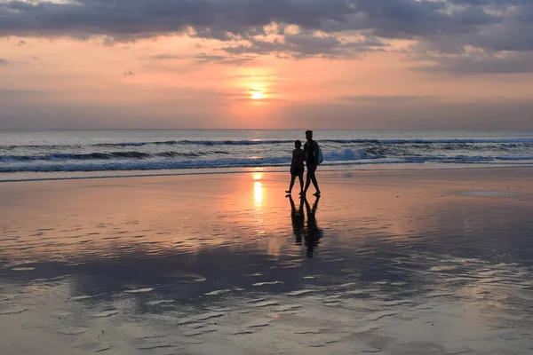  Siyah siluet okyanusa günbatımı sırasında yürüyen küçük bir sörfçü. Seyahat tatil emeklilik yaşam tarzı kavramı. Arka plan
