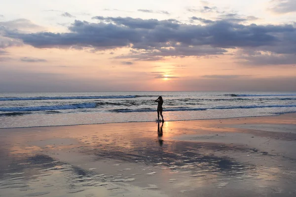 Gökyüzü ve deniz. Güzel gün batımı. Okyanus kumsalda yürüyen genç kadın silüeti. Günbatımı parlak gökyüzü okyanus plaj tatil sırasında doğanın güzelliği genç kadın sahiptir. Mutlu ücretsiz yaşam kavramı