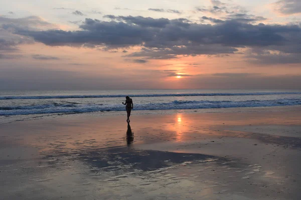 Gökyüzü ve deniz. Güzel gün batımı. Okyanus kumsalda yürüyen genç kadın silüeti. Günbatımı parlak gökyüzü okyanus plaj, Genç kadın doğanın güzelliği tatillerde sahiptir.