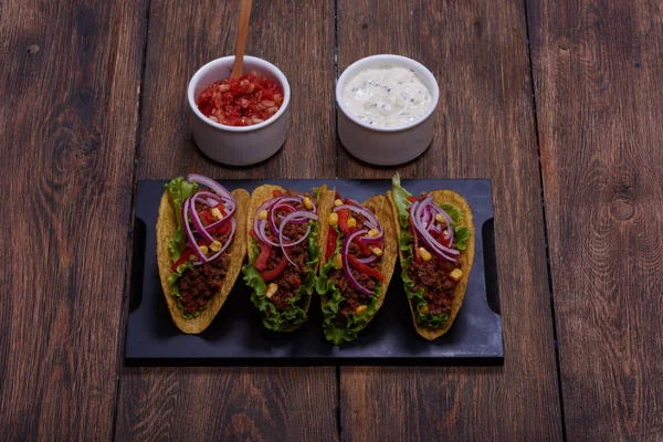 Lezzetli Meksika tacos kırmızı domates, mor soğan, yeşil salata, Mısır ve kıyma cips içinde. Beyaz ekşi krema ve geleneksel yemek için kırmızı salsa sos          