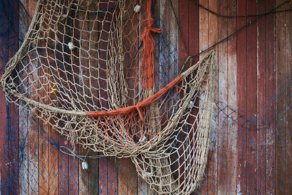 Fishing net, vintage style. Old fishing nets hanging on dark wooden facade of fishing cabins.