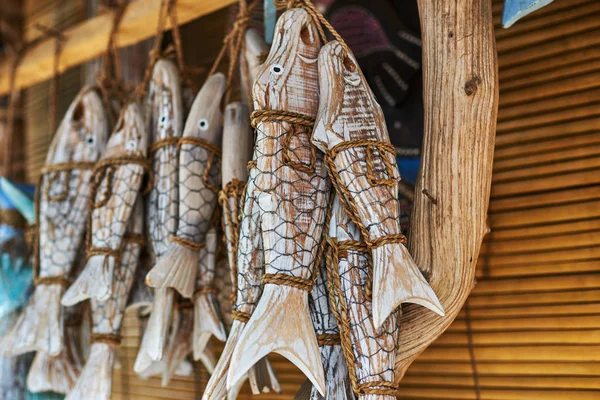 Souvenir background. Travel and tourism concept. Hanging  handicraft  decoration wooden carved fish. Art and craft  market. Display of handicraft decoration in the open market. Selective focus