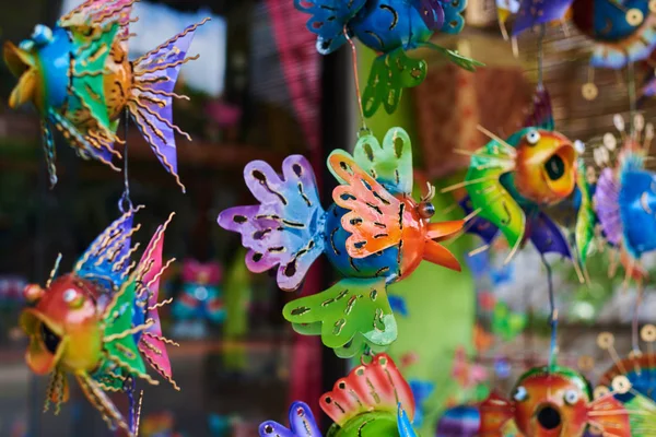 Colorful  souvenir background. Hanging decoration in the market. Handmade metallic fish hanging on the tourist market. Sale of souvenirs. Funny handmade fishes with bright colorful patterned.
