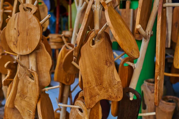 Wooden cutting boards from natural wood in the market. Handmade souvenirs. Craft eco product of untreated wood for sale. Wooden crafts on a stall in the market. Walnut handmade wood cutting board.