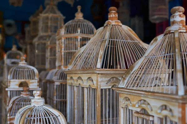 Many different sizes, colorful, wooden cages for birds. The store for selling cages for birds is completely filled with various colorful handmade cages. Multicolored background. Selective focus.