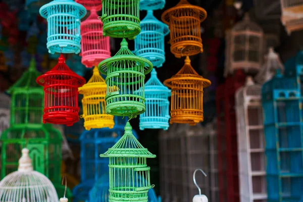 Colorful souvenir background. Many different sizes, colorful, wooden cages for birds. The store for selling cages for birds is completely filled with various colorful handmade cages. Selective focus.