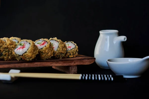 传统的日本料理 天妇罗寿司卷由熏鳗鱼和蟹肉制成 配有芥末 姜和酱油 在褐色木板上放上黑色背景的寿司 选择性聚焦 — 图库照片