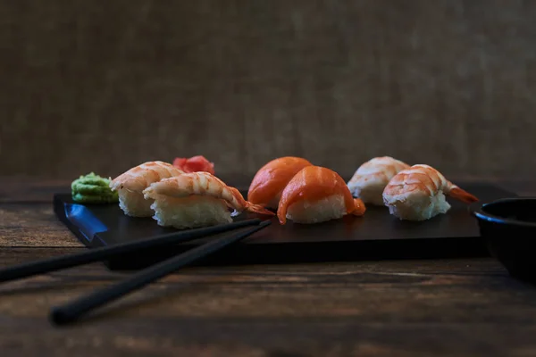 寿司卷配鲑鱼 小牛鱼子酱和奶酪 寿司菜单 日本料理 在黑暗背景下的寿司 日本料理 寿司套装 寿司和寿司卷在木盘子上 选择性对焦 — 图库照片