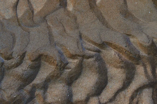 Wave lines in the sand. Texture. The sand on the beach. Wave and sand pattern on the surface of a beach. Sand pattern at the beach can be used as a background for any inscriptions and illustrations.