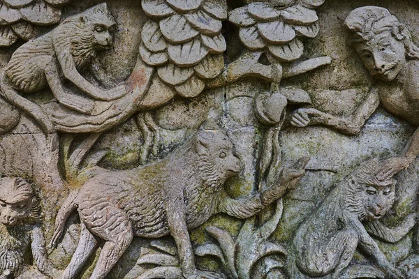 Detail of relief  wall with stone carving in Bali,Indonesia. Temple with traditional stone carving indonesia. Relief sculpture on the wall of a Buddhist temple. Ancient stone carving covered with moss