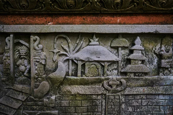 Detail of relief  wall with stone carving in Bali,Indonesia. Temple with traditional stone carving indonesia. Relief sculpture on the wall of a Buddhist temple. Ancient stone carving covered with moss
