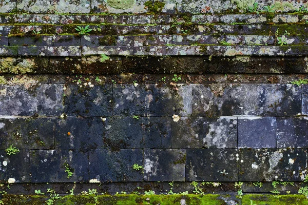 Ancient wall of the temple complex. Green moss on stone. Old masonry stone wall pattern. Empty wall close up. Durability concept. Copy space for text.