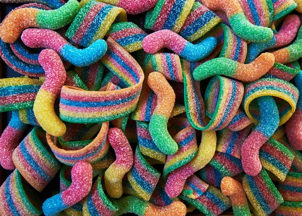 Different fruit candies. Colorful bright chewy candies covered with sugar. Rainbow ribbon candies. Colorful jelly candies close up as a bright joyful background. Top view. Candy background