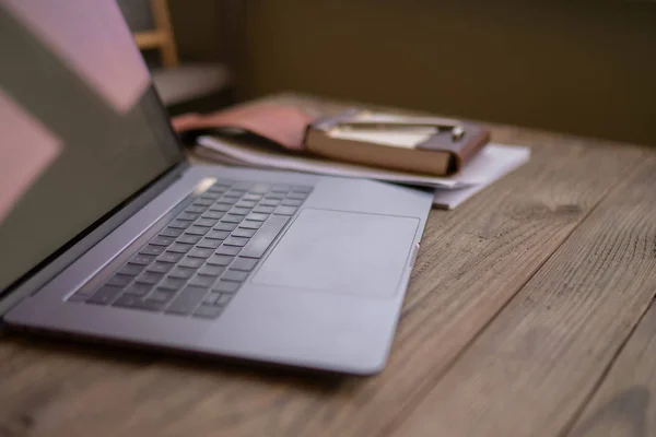 Modern loft interior office desk with laptop, notebook on the brown background. Close-up of open laptop on wooden table. Empty workplace. Conceptual workspace. Blurred background. Selective focus.