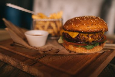 Fast food yemek. Kraft kağıt, patates cipsi et burgeri. Patates kızartması, hamburger, mayonez ve soslar ahşap üzerinde. Menü veya tarifi arka plan. Patates kızartması ufaklık sepet ve ketçap kase.