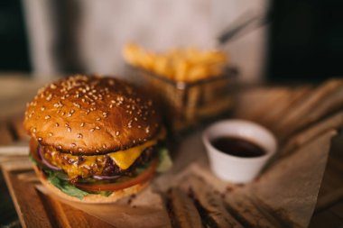Lezzetli sığır eti burger taze patates ile. Fast food kavramı. Izgara sığır eti burger marul ve mayonez rustik ahşap masa üzerinde kahverengi kağıt parçaları yılları arasında görev yapmıştır. Bir Amerikan burger patates kızartması ile