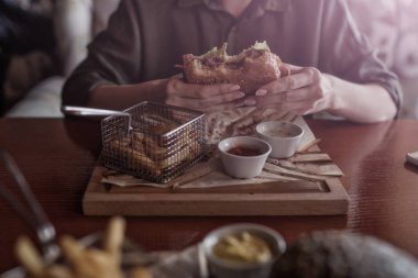El lokanta hamburger, Amerikan sağlıksız kalori yemek tutan genç kız. Izgara hamburger önden görünüm aç insan. İnsanlar ve beslenme kavramı. Fast food. Tonlu görüntü.