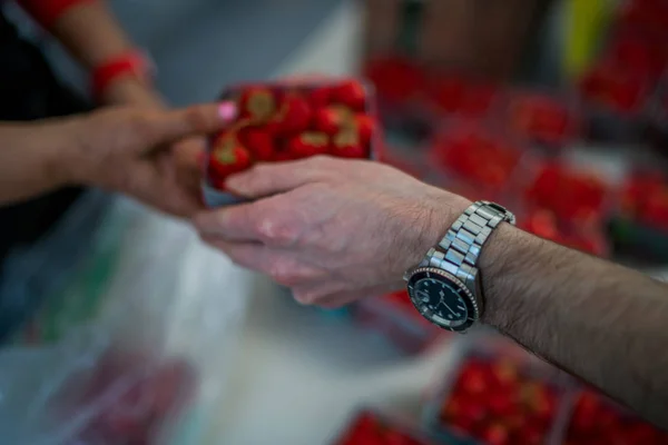 Marketplace with different fruits. Buyer\'s and sellers hands on colorful berry background outdoors. Sale, shopping and people concept. Close up buying berry at street food market. Selective focus.