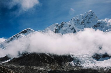 Yüksek dağlar karlı zirveleri parlak güneşli bir günde bulutlara Nepal ile. Renkli manzara güzel kayalar ve dramatik bulutlu gökyüzü. Doğa arka plan. Şaşırtıcı dağlar. Everest yol ana kampta.