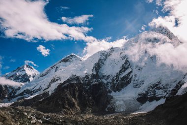 Yüksek dağlar karlı zirveleri parlak güneşli bir günde bulutlara Nepal ile. Renkli manzara güzel kayalar ve dramatik bulutlu gökyüzü. Doğa arka plan. Şaşırtıcı dağlar. Everest yol ana kampta.