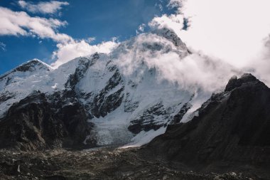 Yüksek dağlar karlı zirveleri parlak güneşli bir günde bulutlara Nepal ile. Renkli manzara güzel kayalar ve dramatik bulutlu gökyüzü. Doğa arka plan. Şaşırtıcı dağlar. Everest yol ana kampta.