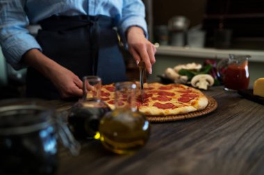 Taze kesme kadın ev yapımı pizza rustik mutfak arka plan üzerinde pişmiş. Mantar ve Jambon dilimleri lezzetli pizza kesilmiş. Peynir ve domates ahşap masa üzerinde. Sağlıklı gıdalar, kavram pişirme.