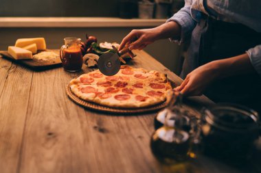Taze kesme kadın ev yapımı pizza rustik mutfak arka plan üzerinde pişmiş. Mantar ve Jambon dilimleri lezzetli pizza kesilmiş. Peynir ve domates ahşap masa üzerinde. Sağlıklı gıdalar, kavram pişirme.