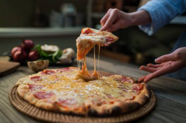 Sıcak pizza dilim peynir rustik ahşap bir masa üzerinde erime ile. Gıda katkı maddeleri ve yemek pişirmek için baharat. Mantar, domates, peynir, soğan, yağ, karabiber, tuz, fesleğen, zeytin ve lezzetli İtalyan pizza.