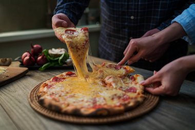 Sıcak biberli pizza, büyük peynir öğle veya akşam yemeği peynir ile dilim. Lezzetli lezzetli lokanta İtalyanca Side'de klasik ahşap tahta masada geleneksel görüntüleyin. Dilim pizza alarak elleriyle.