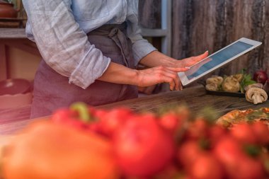Genç kadın mutfakta bir tablet bilgisayarda tarifi arıyorum. Sağlıklı gıda. Sağlıklı bir yaşam tarzı. Evde yemek. Yemek tarifi tablet ekranında göre. Teknoloji kavramı. Tonlu görüntü.