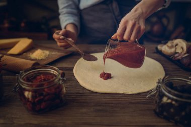 Taze orijinal İtalyan ham pizza ve malzemelerin üzerine ahşap masa, hazırlık, geleneksel tarzda. Ev yapımı pizza ev bir mutfak ahşap bir masa üzerinde yemek kadın. Pişirme, yiyecek ve insan kavramı.