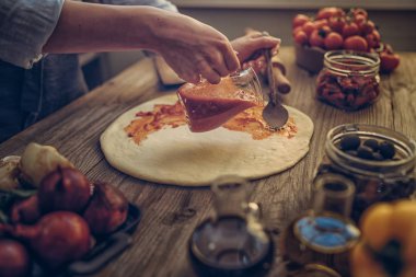 Taze orijinal İtalyan ham pizza ve malzemelerin üzerine ahşap masa, hazırlık, geleneksel tarzda. Ev yapımı pizza ev bir mutfak ahşap bir masa üzerinde yemek kadın. Pişirme, yiyecek ve insan kavramı.