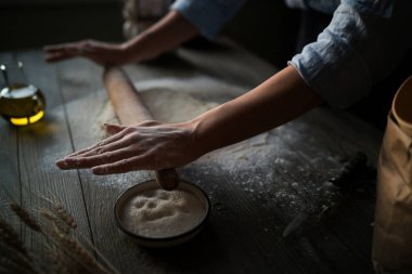 Rustik ahşap masa üzerinde malzemelerle pizza hamuru. Kadın oklava ile un pişirme arka plan, menü, yemek tarifi, koyu kahverengi masaya dokunmayın. Ahşap tablo bir fırın ekmek hamur hazırlama.