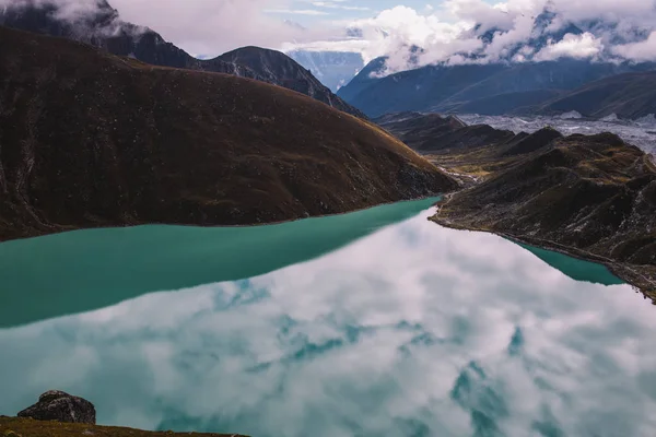 Himalayas mountains. Lake in the mountains, rocks in clouds. View on the lake Gokyo Ri. Colorful landscape with beautiful rocks and dramatic cloudys. Sky is reflected in the lake. Amazing mountains.