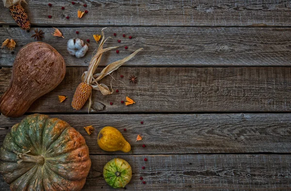 Thanksgiving background. Pumpkins, apples, leaves, cotton flower and spices on brown wooden background. Seasonal fall background for Thanksgiving or Halloween. Design mock up. Horizontal, toned image.