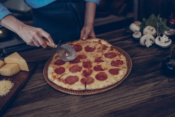 Italian style dinner. Homemade pizza with tomato and basil in board on the wooden rustic table and ingredients for cooking. Chef hands preparing homemade food.Healthy foods, cooking concept.