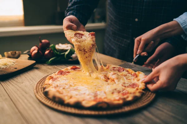 Sıcak biberli pizza, büyük peynir öğle veya akşam yemeği peynir ile dilim. Lezzetli lezzetli lokanta İtalyanca Side'de klasik ahşap tahta masada geleneksel görüntüleyin. Dilim pizza alarak elleriyle.