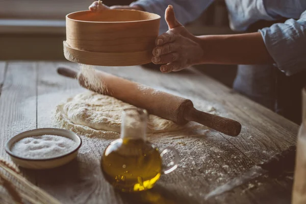 Ev yapımı çiğ hamur rustik ahşap bir masa üzerinde. Pizza yapma. Bir oklava ile hamur. Un, tereyağı, buğday spikelets. Yemek ve gıda kavramı. Tonlu görüntü.