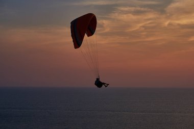 Günbatımı okyanus. Gün batımı arka plan üzerinde yalnız bir paraşüt silüeti. Gökyüzü, bulutlar ve su. Güzel sakin bir sahne. Doğanın doğal kompozisyon. Manzara. Açık hava etkinlikleri kavramı.