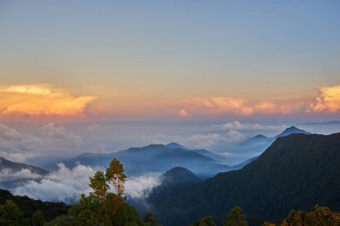Dağ manzarası, gündoğumu. Kayalar, alçak bulutlar, mavi gökyüzü ve bulutlar dağ tepe üzerinden güneş doğarken görüntüleyin. Renkli doğa arka plan. Macera. Seyahat. Güzel sahne.