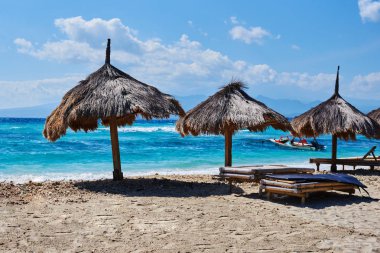 Birkaç plaj şemsiyeleri turkuaz okyanus zemin karşı açık güneşli bir günde thatched. Cennet tropikal Adası'nın kıyısında, saman şemsiye ile boş kum plaj. Seyahat kavramı. 