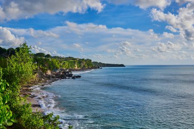 Yemyeşil tropik bitkiler ile deniz kum plaj manzarası. Pitoresk ve muhteşem sahne. Güzel manzara, tropikal kayalık plaj üzerinde arka plan güneşli gökyüzü bulutlu. Yaz tatili. Güzellik Dünya.