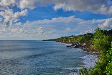 Yemyeşil tropik bitkiler ile deniz kum plaj manzarası. Pitoresk ve muhteşem sahne. Güzel manzara, tropikal kayalık plaj üzerinde arka plan güneşli gökyüzü bulutlu. Yaz tatili. Güzellik Dünya.