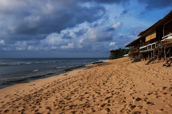 Typical wooden bars  on the beautiful tropical beach with lush vegetation fringing golden sand and a tranquil ocean with gentle surf breaking on the beach. Popular deserted beach Bali Indonesia.