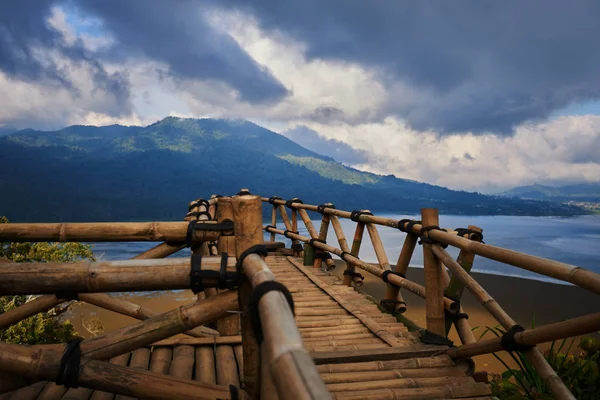 View from a cliff  through viewing platform on mountain slope. Low cloud shrouds the distant mountains above the waters of the lake. A bamboo viewing platform. The observation deck. Selective focus.