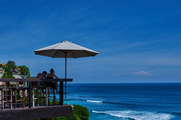 青い海を背景に若いカップルの背面します 幸せなカップルは 夏の休暇中に美しい景色をリラックスします オーシャン ビューの前に穏やかで平和なリラックスした午後を楽しんでください — ストック写真