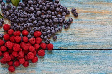 Yaban mersini ve ahududu eski mavi ahşap arka plan üzerinde.